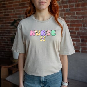 Cute Nurse Shirt – Colorful Pastel Letters with Bandage Graphic, Fun Nurse Appreciation Gift, Kawaii Medical T-Shirt for Women