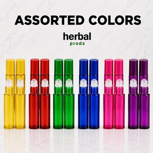 May include: A collection of twelve glass roller bottles arranged in pairs, featuring yellow, red, green, blue, pink, and purple colors. Each bottle has a matching cap and a clear roller ball. The text ASSORTED COLORS and herbal prods is visible.