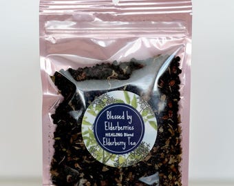 May include: A pink resealable pouch filled with a blend of dried herbs and berries. The pouch has a label that reads "Blessed by Elderberries HEALING Blend Elderberry Tea".