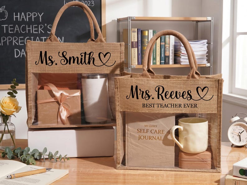 May include: Two rectangular jute tote bags with brown fabric handles and a clear plastic front window. The left bag features the text Ms. Smith with a heart icon. The right bag displays Mrs. Reeves and the text BEST TEACHER EVER with a heart icon.