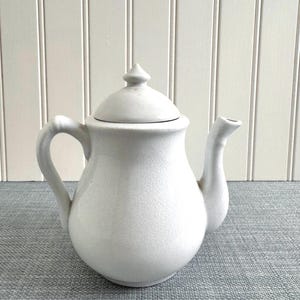 May include: A set of three ceramic mugs with a speckled, matte finish. The mugs are in shades of cream, light gray, and dark gray. Each mug has a simple, minimalist design, perfect for coffee or tea.