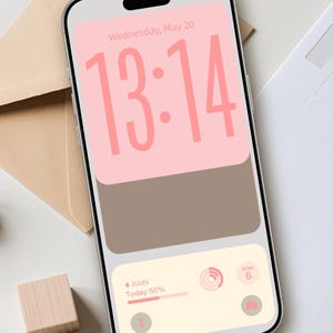 Op de afbeelding: Een smartphone toont een aangepast vergrendelscherm met een roze en bruin kleurenschema. De tijd is 13:14, met de datum woensdag 20 mei bovenaan. Het onderste gedeelte toont weersinformatie en een kalenderdatum. Ontwerp door DreamScreenz.