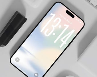 Op de afbeelding: Een zwarte smartphone met een pastelkleurig scherm met de tijd 13:14 en de datum dinsdag 20 mei. De telefoon is omgeven door een wit toetsenbord, een witte muis, een witte oplaadcase en een zwarte stylus. Bovenaanzicht.