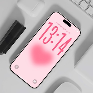 May include: A smartphone with a pink heart-shaped background displays the time 13:14 on the screen. A white keyboard, wireless earbuds, and a black stylus are also visible. The text "Wednesday, May 20" is displayed on the screen. The image is labeled "Design by DreamScreenz."
