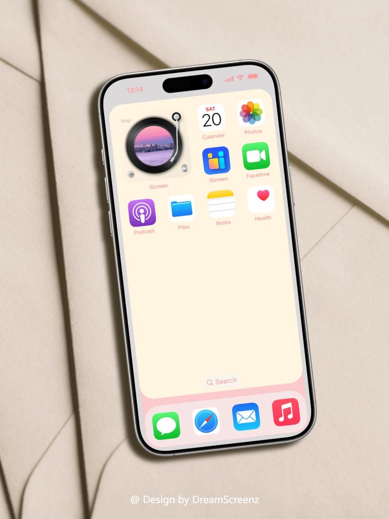 Op de afbeelding: Een smartphone met een lichtroze en wit scherm toont app-iconen, waaronder een kalender, foto's en een podcast-app. Het scherm toont de tijd als 13:14. De telefoon heeft een zwart camera-gedeelte aan de bovenkant en een roze onderrand. Design by DreamScreenz.
