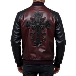 May include: Black and burgundy bomber jacket with a large, ornate cross design on the back. The jacket features black sleeves and a burgundy body, with a ribbed collar and cuffs. The cross is a detailed, embossed design.