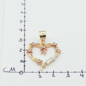 May include: A gold-toned heart pendant with a 'Mother' inscription. The heart is adorned with small, clear gemstones and rose gold accents. The pendant is approximately 1.5 cm wide.