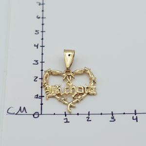 May include: A gold-coloured pendant in the shape of a heart, with the word "Richote" in stylised lettering. The heart is framed by a barbed wire design. The pendant measures approximately 2.5 cm in width.