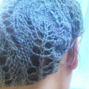 May include: A hand-knitted blue hat with a delicate openwork pattern. The hat is made of a soft, textured yarn, and the openwork design creates a lacy effect. The hat is a stylish accessory.