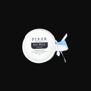 Puede incluir: Taza de cer&aacute;mica blanca con el texto "PIXAR" y "RAE DUNN" en letras negras. La taza tiene un asa y una etiqueta azul adjunta. La taza es apta para lavavajillas y microondas.