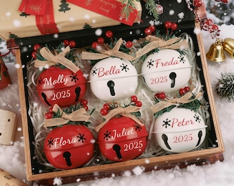 以下が含まれることがあります： 木製の箱に入った、6つのパーソナライズされたクリスマスベルオーナメントのセット。 赤いベル3つと白いベル3つには、名前、雪の結晶、2025年が装飾されています。 各ベルは鍵穴のデザインで、ジュートのリボンと赤いベリーで飾られています。