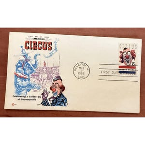 May include: Vintage circus-themed envelope with a clown illustration and a circus stamp. The envelope is postmarked May 2, 1966, from Delavan, WI. Text includes "First Day of Issue" and "Celebrating a Golden Era of Showmanship."