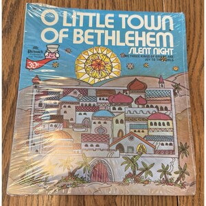 May include: A vintage vinyl record titled "O Little Town of Bethlehem" with a colorful illustration of a town. The album cover features the text "Silent Night" and "We Three Kings of Orient Are Joy to the World."