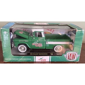 May include: A white ceramic mug with a black handle and the text "But First, Coffee" in a bold, black font. The mug is set against a blurred background, suggesting a cozy setting. The mug appears to be approximately 4 inches tall.