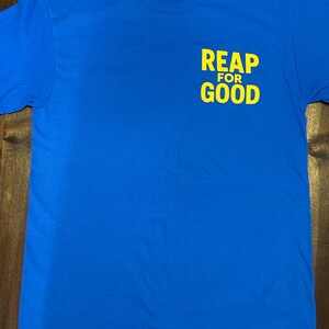 Op de afbeelding: Een koninklijk blauw T-shirt met de tekst "REAP FOR GOOD" in geel op de voorkant.