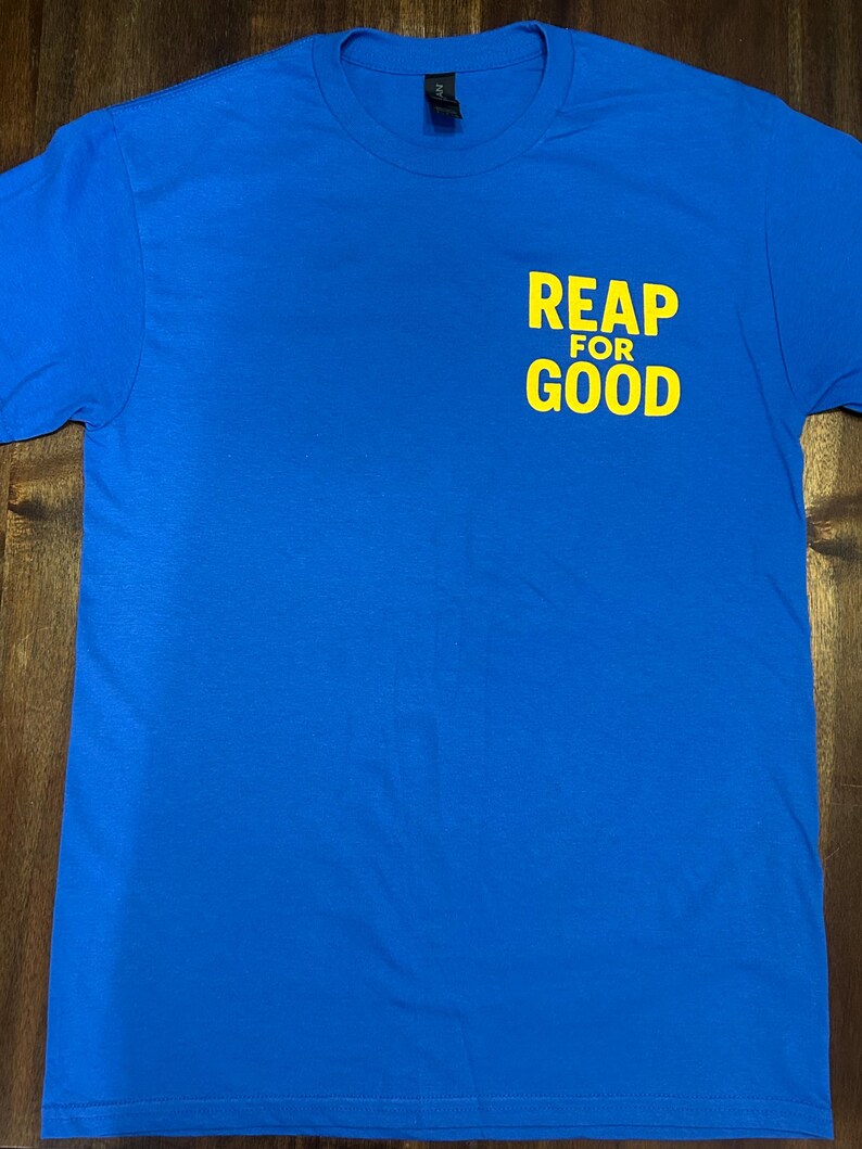 Op de afbeelding: Een koninklijk blauw T-shirt met de tekst "REAP FOR GOOD" in geel op de voorkant.
