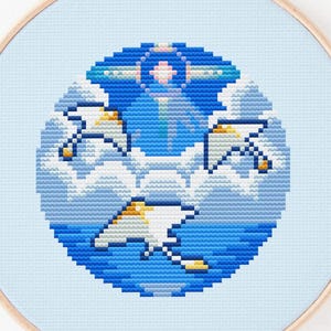 May include: A cross-stitch embroidery hoop featuring a blue and white design of seagulls flying over the ocean and clouds. The design is set against a light blue background. The text "@ochai stitch cafe" is at the bottom.