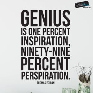 May include: A black and white inspirational quote by Thomas Edison: "Genius is one percent inspiration, ninety-nine percent perspiration." The quote is displayed on a white wall with a decorative vase and green glass blocks in the foreground.