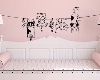 May include: A white daybed with a pink and black polka dot patterned mattress and two pink cylindrical pillows. A black and white cat-themed wall decal with five cats hanging on a clothesline is above the daybed.