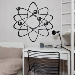 May include: A white desk with a black metal chair, a black lamp, and a small potted plant. The wall behind the desk has a black and white atom symbol sticker.