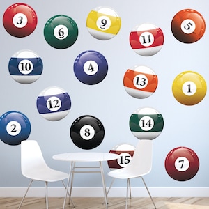 May include: A set of 15 billiard balls with numbers 1 through 15, displayed on a light blue wall. The balls are arranged in a random pattern, with some overlapping. The balls are all different colors, including red, yellow, blue, green, and black.