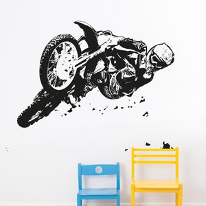 May include: Black and white silhouette of a motocross rider performing a trick on a dirt bike. The rider is wearing a helmet and goggles. The image is on a white background.