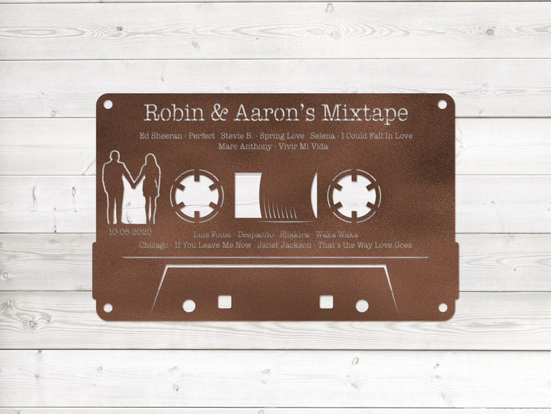 May include: A brown metal cassette tape with a white outline and text that reads "Robin & Aaron's Mixtape". The cassette tape has a date of "10-05-2020" and a list of songs with artists, including "Ed Sheeran - Perfect", "Stevie B. - Spring Love", "Selena - I Could Fall In Love", "Marc Anthony - Vivir Mi Vida", "Luis Fonsi - Despacito", "Shakira - Waka Waka", "Chicago - If You Leave Me Now", and "Janet Jackson - That's the Way Love Goes".