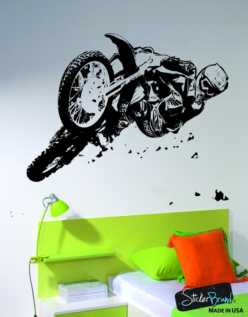 May include: Black and white silhouette of a motocross rider performing a stunt on a dirt bike. The rider is in mid-air, with the bike's front wheel off the ground. The image is set against a white background.
