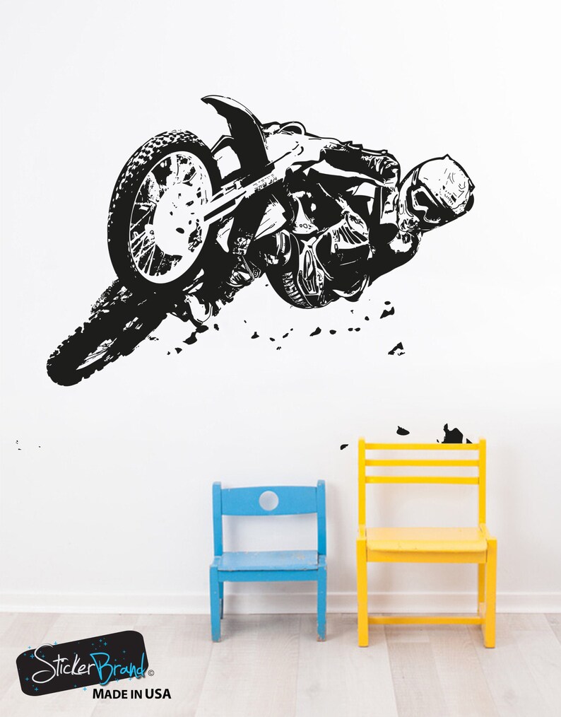 May include: Black and white silhouette of a motocross rider performing a trick on a dirt bike. The rider is wearing a helmet and goggles. The image is on a white background.