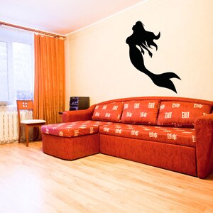 May include: A red sectional sofa with white patterned cushions in a living room with a black silhouette of a mermaid on the wall.