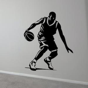 May include: Black and white silhouette of a basketball player dribbling a ball. The player is wearing a jersey and shorts. The image is a simple design, perfect for a sports-themed wall decal.