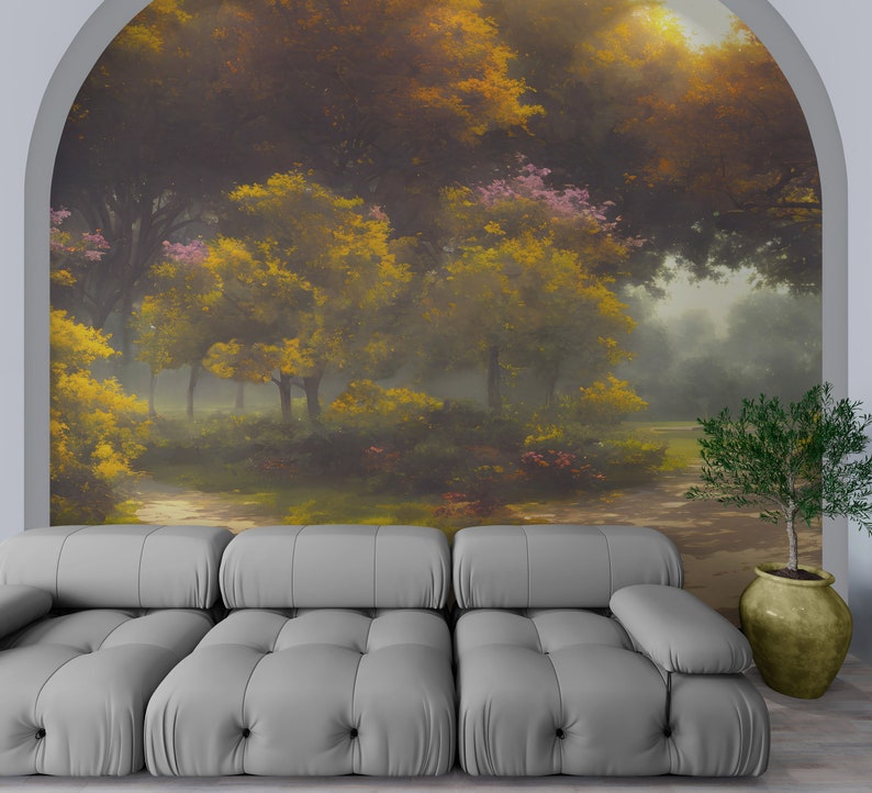 Pode incluir: Um sof&aacute; capiton&ecirc; cinza-claro est&aacute; posicionado em frente a um grande mural de parede arqueado que retrata uma cena de floresta com &aacute;rvores amarelo-douradas, folhagem verde e luz suave. Uma pequena planta verde num vaso bege arredondado.