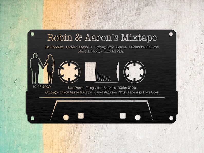 May include: A black cassette tape with a white design. The tape is labeled "Robin & Aaron's Mixtape" and includes a list of songs and artists. The date "10-05-2020" is printed on the tape.