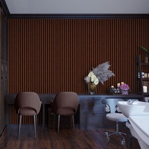 May include: A salon interior with two brown chairs, a wooden desk with drawers, and a white sink with a white countertop. The wall is covered in brown vertical wood panels. There are white towels and a vase of flowers on the desk.