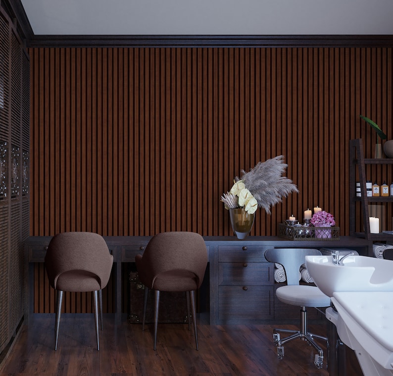 May include: A salon interior with two brown chairs, a wooden desk with drawers, and a white sink with a white countertop. The wall is covered in brown vertical wood panels. There are white towels and a vase of flowers on the desk.