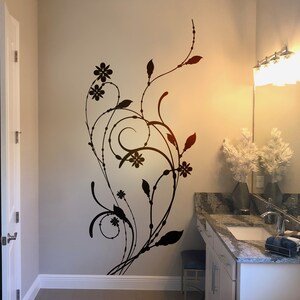 May include: A black floral design wall decal with intricate swirls and leaves, adding a touch of elegance to a bathroom with a white vanity and a granite countertop.