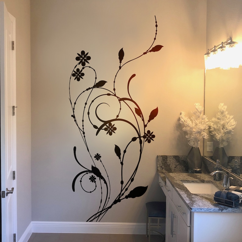 May include: A black floral design wall decal with intricate swirls and leaves, adding a touch of elegance to a bathroom with a white vanity and a granite countertop.