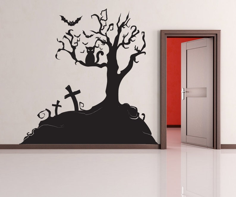 May include: Black and white Halloween wall decal featuring a spooky tree with bats, a cat, and three tombstones. The decal is applied to a white wall with a door in the background.