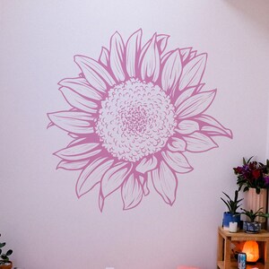 Puede incluir: Una calcoman&iacute;a de pared gr&aacute;fica de girasol rosa y blanco. El girasol est&aacute; dibujado en un estilo realista y detallado.