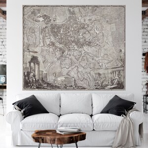 May include: A vintage black and white map of Rome, Italy, with detailed streets and landmarks. The map is framed and hanging on a white wall in a modern living room.