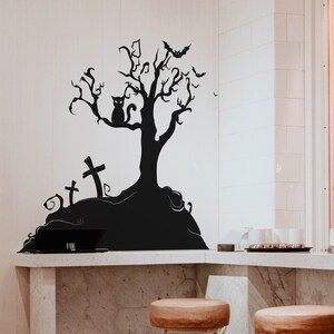 May include: Black and white silhouette wall decal of a spooky tree with a cat, bats, and tombstones. The decal is on a white wall above a marble countertop.