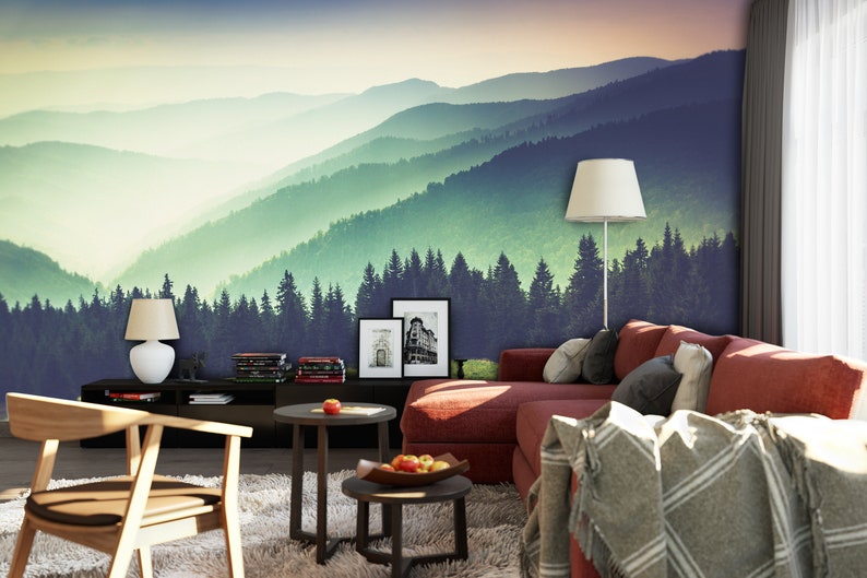 May include: A wall mural featuring a panoramic view of layered mountain ranges and a dense pine forest in shades of green and blue. The scene transitions from a dark foreground to a hazy, light-filled horizon under a soft, gradient sky.