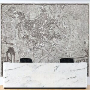 May include: A black and white vintage map of Rome, Italy, printed on a wall behind a white marble reception desk.