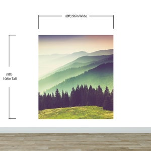 May include: A wall mural featuring a mountain landscape with a grassy foreground, a dense forest of dark green pine trees, and layers of misty blue mountains fading into a soft sunset sky. The mural measures 96 inches wide by 108 inches tall.