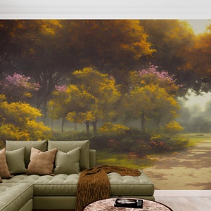 Pode incluir: Um grande mural de parede que retrata uma cena de floresta densa com folhagem amarelo-dourada e verde-escura, flores cor-de-rosa e um caminho iluminado pelo sol. O mural est&aacute; instalado atr&aacute;s de um sof&aacute; de canto verde-s&aacute;lvia com almofadas e manta castanha.