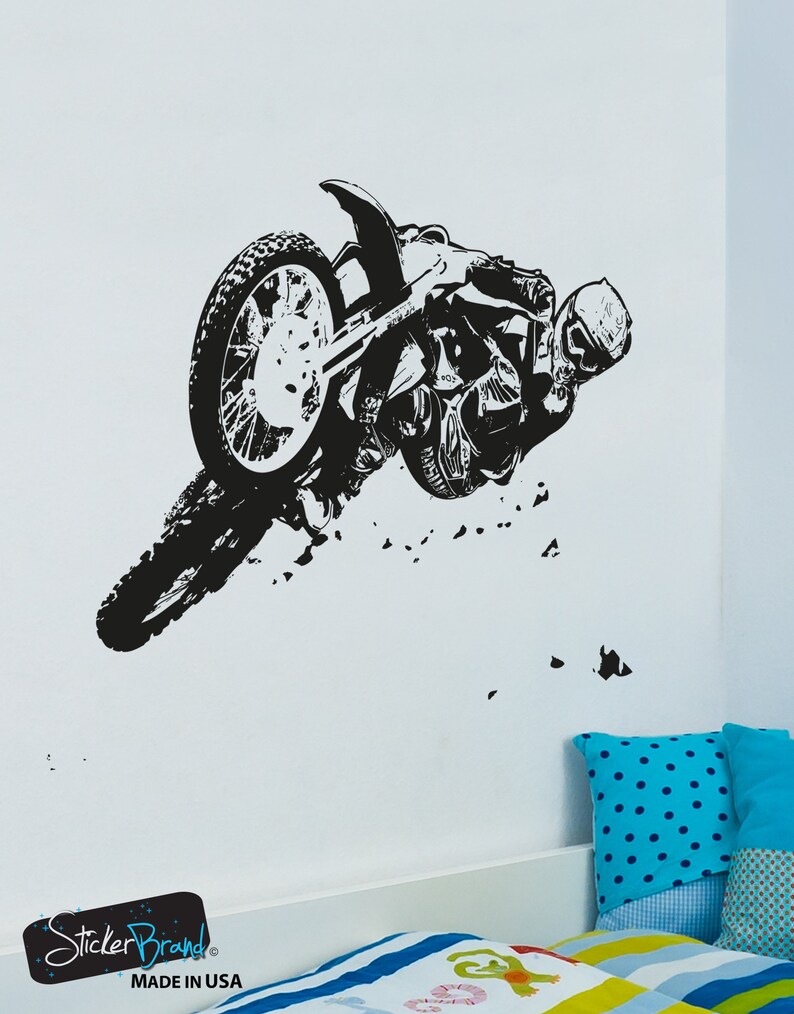 May include: Black and white silhouette of a motocross rider performing a stunt on a dirt bike. The rider is wearing a helmet and goggles. The bike is in mid-air, with the front wheel off the ground. The image is set against a white background.