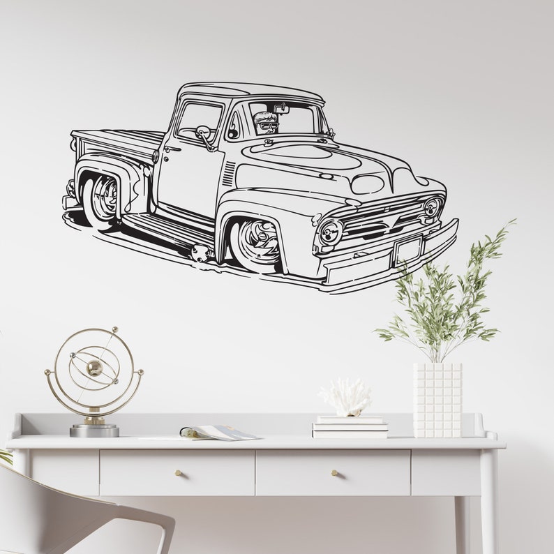 May include: Black and white line art illustration of a vintage pickup truck on a white background. The truck has a large, rounded hood and a long bed. The truck is facing the viewer and is slightly angled to the left. The truck is drawn in a simple, stylized manner.