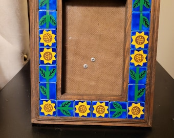 Handcrafted sunflower decorative picture frame featuring a wooden frame inlaid with Talavera-style blue and yellow ceramic tiles.