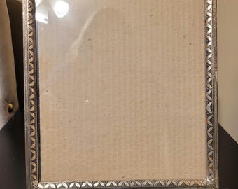 Vintage-style photo frame features a distinctive gold-toned metal embossed border.
