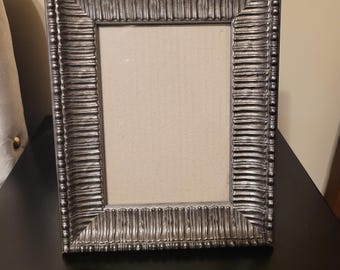 Silver-toned, ornate picture frame with a ribbed design